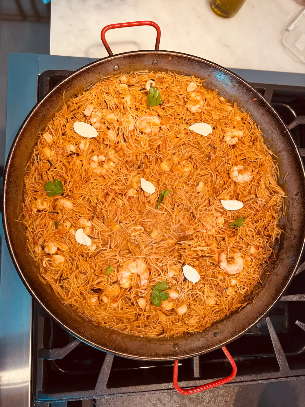Vista cenital de fideuá, la prima de la paella hecha con fideos, con gambas y ajo en una paellera