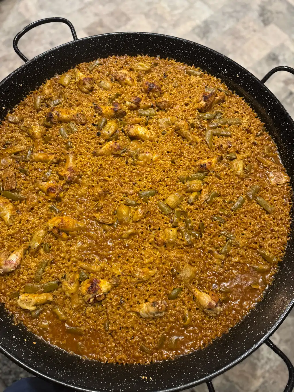 Paella valenciana cocinada en vivo sobre fuego abierto en un evento de Cantábrico en Houston