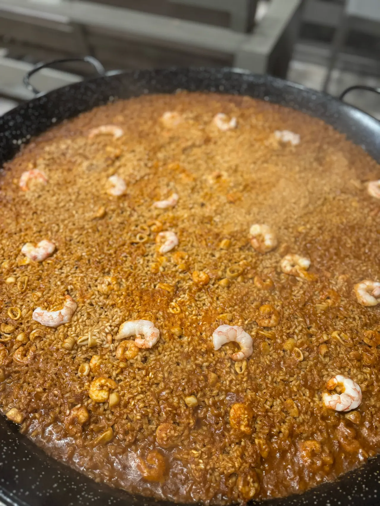Paella valenciana terminada en una paellera negra clásica, cocinada en directo por Cantábrico en Houston