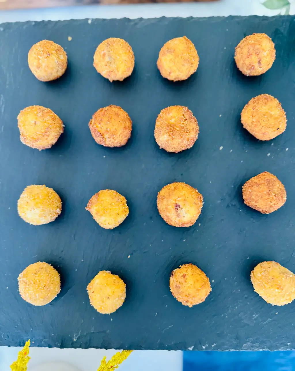 Spanish croquetas arranged in a 4×4 grid on a slate board — Cantábrico tapas plating for a Houston event