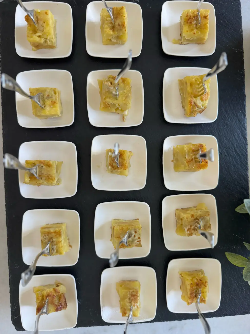 Spanish tortilla de patatas cut into bite-sized cubes and served on individual white plates with serving picks at a Cantábrico event in Houston