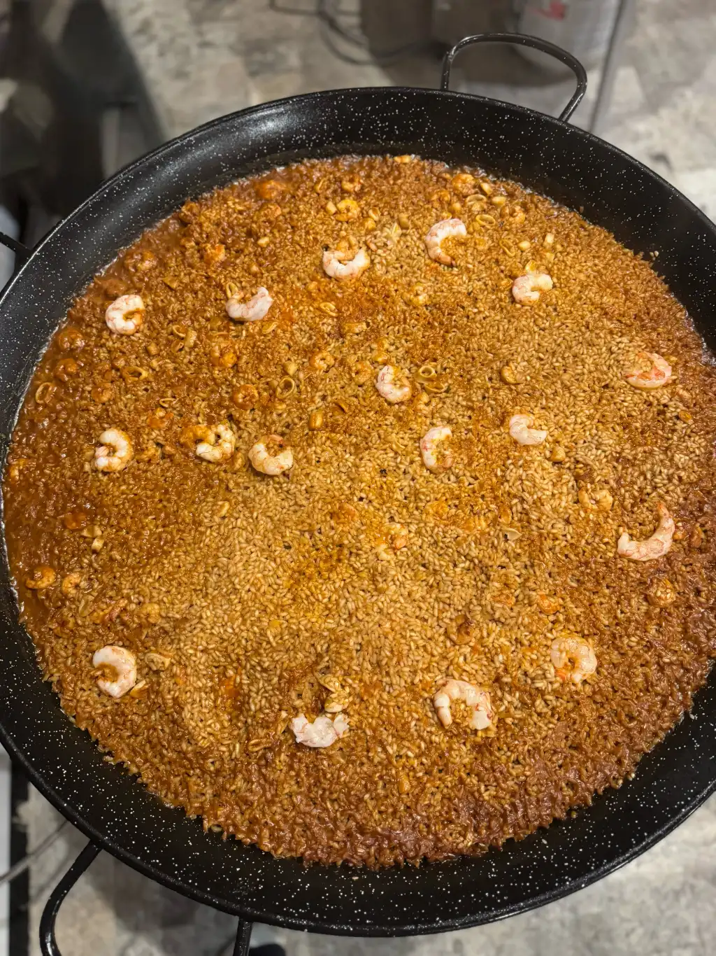 Paella de mariscos finished in the pan, shrimp arranged on top, by Cantábrico Houston