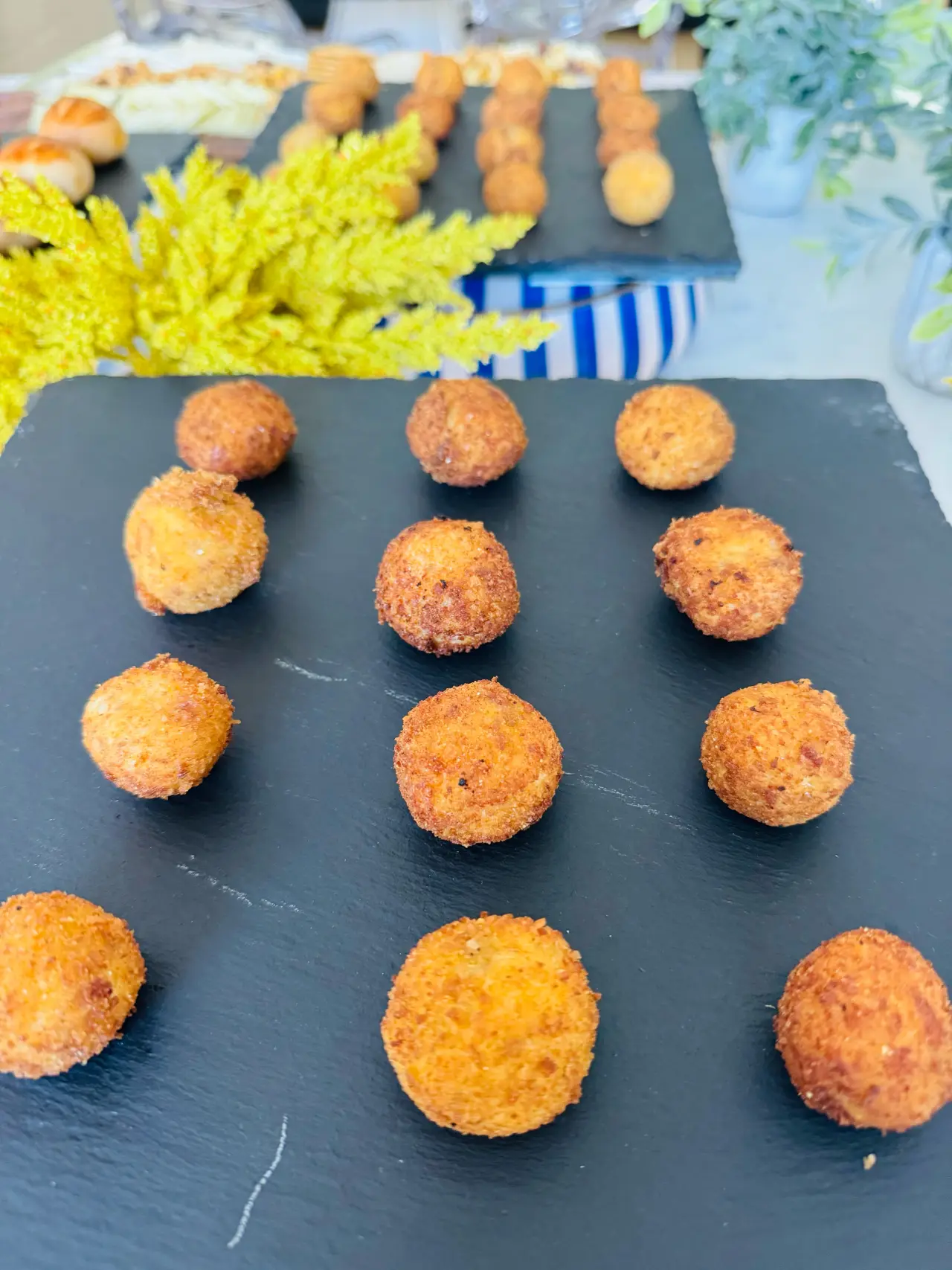 Croquetas españolas dispuestas en cuadrícula sobre pizarra, emplatado de tapas de Cantábrico para una boda en Houston