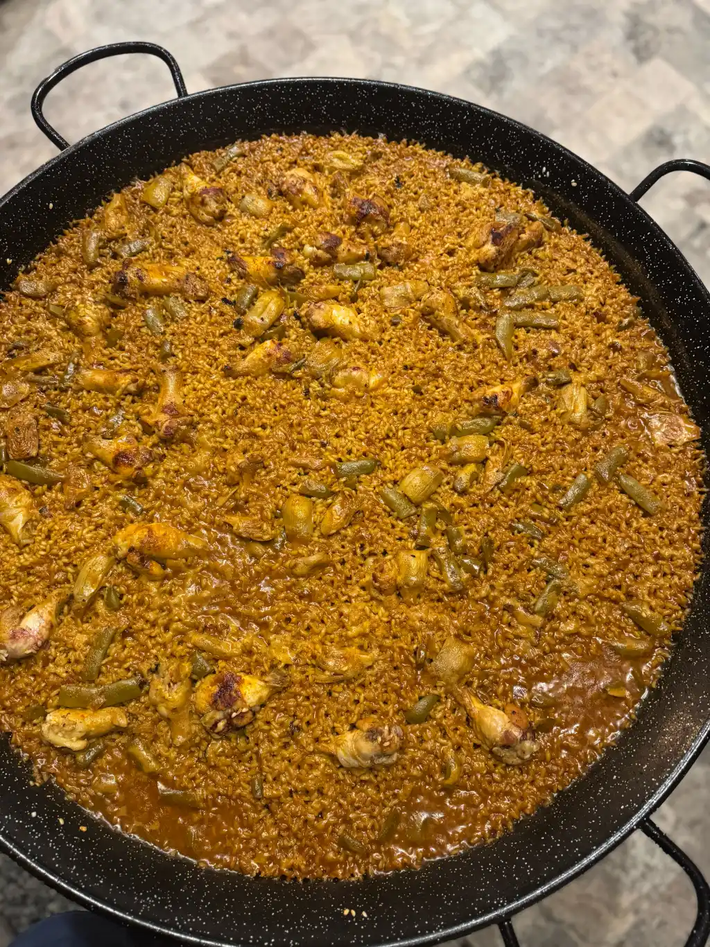 Paella cocinada en vivo a fuego abierto en paellera grande durante una boda con Cantábrico en Houston